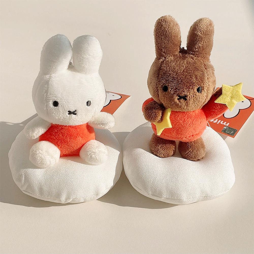 Two miffy and Melanie plush toys, one white and one brown, sitting on white clouds