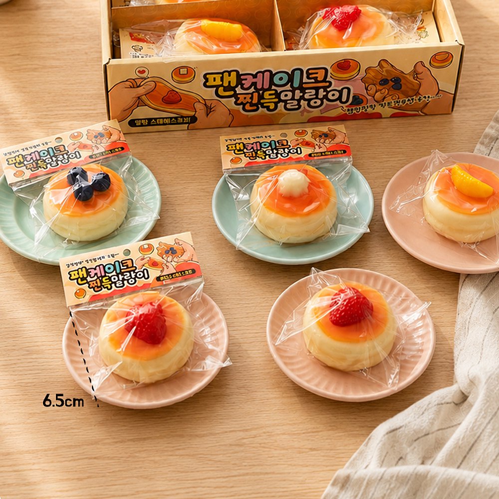 Individually packaged pancake squishy toys with Korean labels laid out next to a retail display box on small pastel plates, ideal party favor goodie bag filler and Christmas holiday gift set