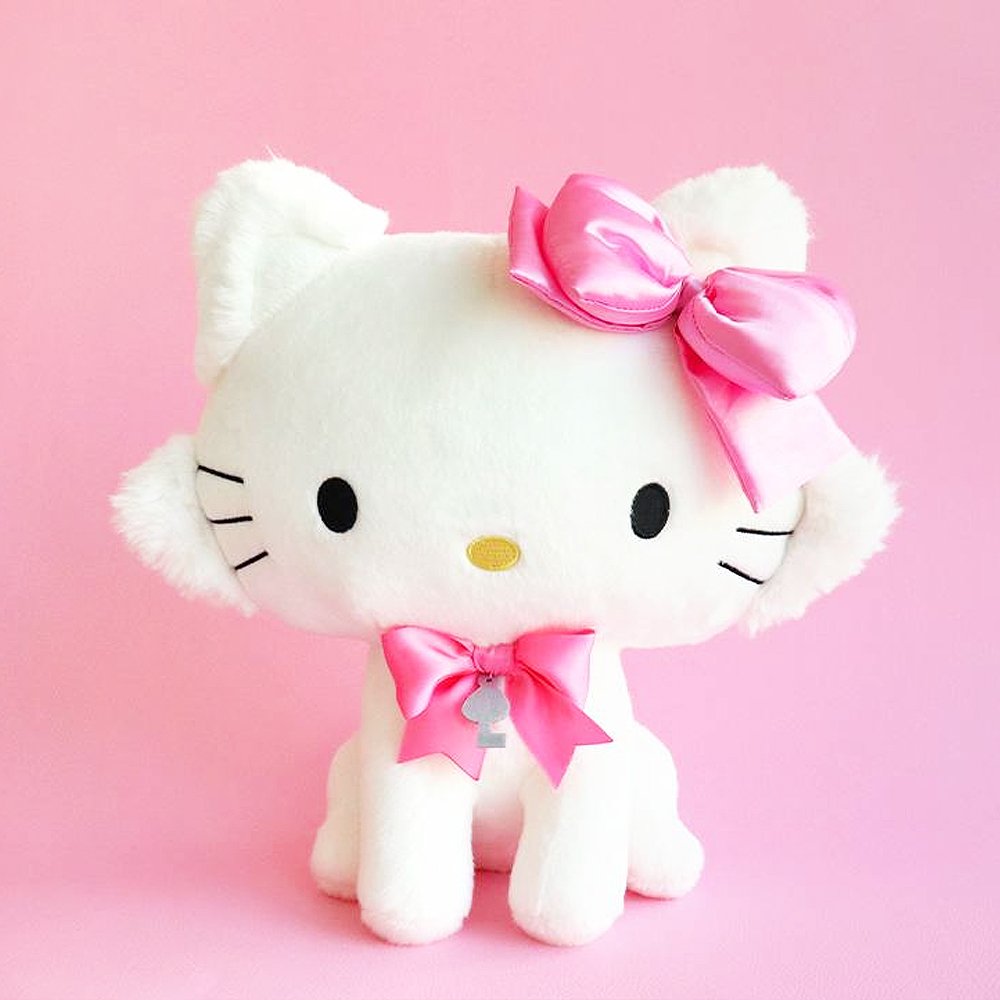 Sanrio Charmmy Kitty plush toy resembling a white cat with a large pink bow on its head and additional pink bows around its neck.