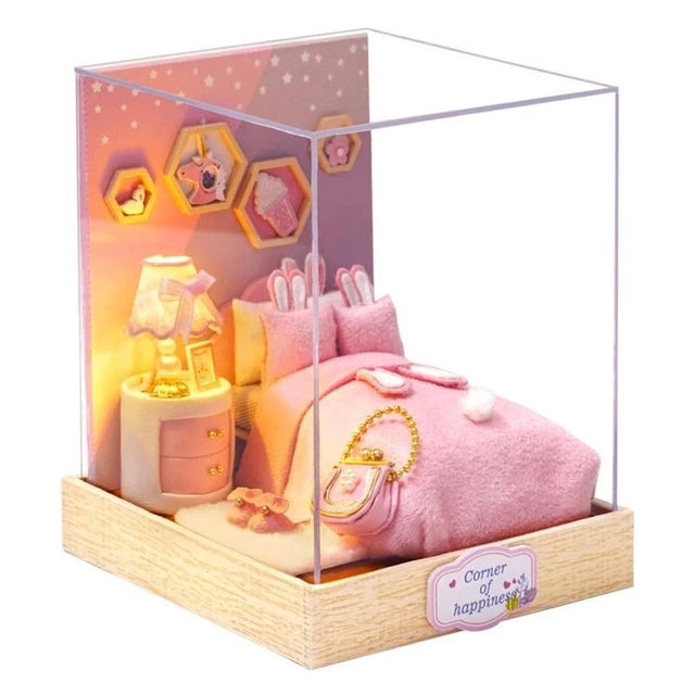 A whimsical DIY miniature bedroom featuring a plush pink bed with bunny pillows, a glowing bedside lamp, and starry wall decor