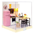 A detailed 3D DIY miniature kitchen model featuring a pink retro refrigerator, white cabinetry, and a small breakfast bar with stools