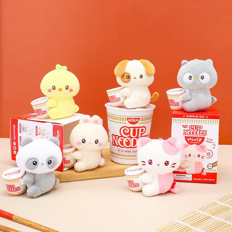 Six officially licensed Anirollz Miniz plush figures, including a panda, cat, and puppy, each holding a miniature Nissin Cup Noodles container. The plushies are displayed alongside their red and white "Cup Noodles Miniz" surprise blind boxes.