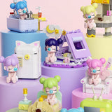 A collection of officially licensed building block sets featuring Baby Nanci in various home scenes like a bathtub, a bed, and next to a retro TV. The figures have colorful hair and are surrounded by pastel-colored furniture and accessories.