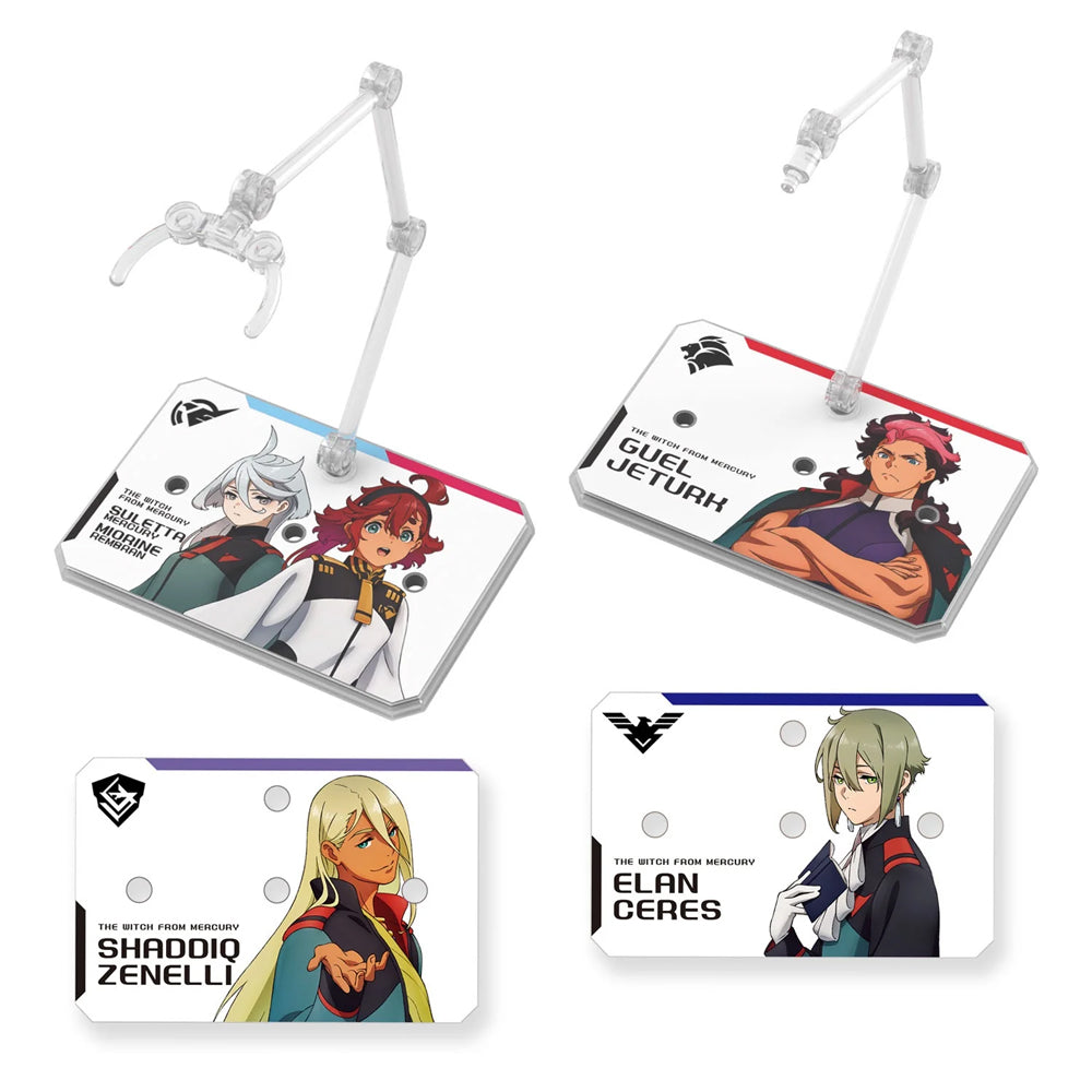 Two officially licensed Bandai Action Base 6 stands in clear plastic. Each features a rectangular base and an articulated support arm, customized with different plastic stickers showing portraits of characters like Suletta, Miorine, Guel, Shaddiq, and Elan.