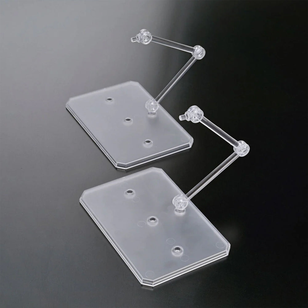 Two officially licensed Bandai Action Base 6 stands in clear plastic. Each features a rectangular base and an articulated support arm, customized with different plastic stickers showing portraits of characters like Suletta, Miorine, Guel, Shaddiq, and Elan.