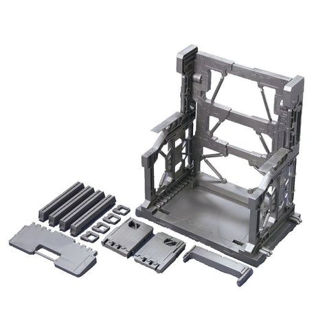 An officially licensed Bandai System Base 001 model kit display stand in metallic gunmetal gray. The retail packaging shows the mechanical hangar holding 1/144 scale Gunpla figures, highlighting its adjustable structural parts and industrial detail.
