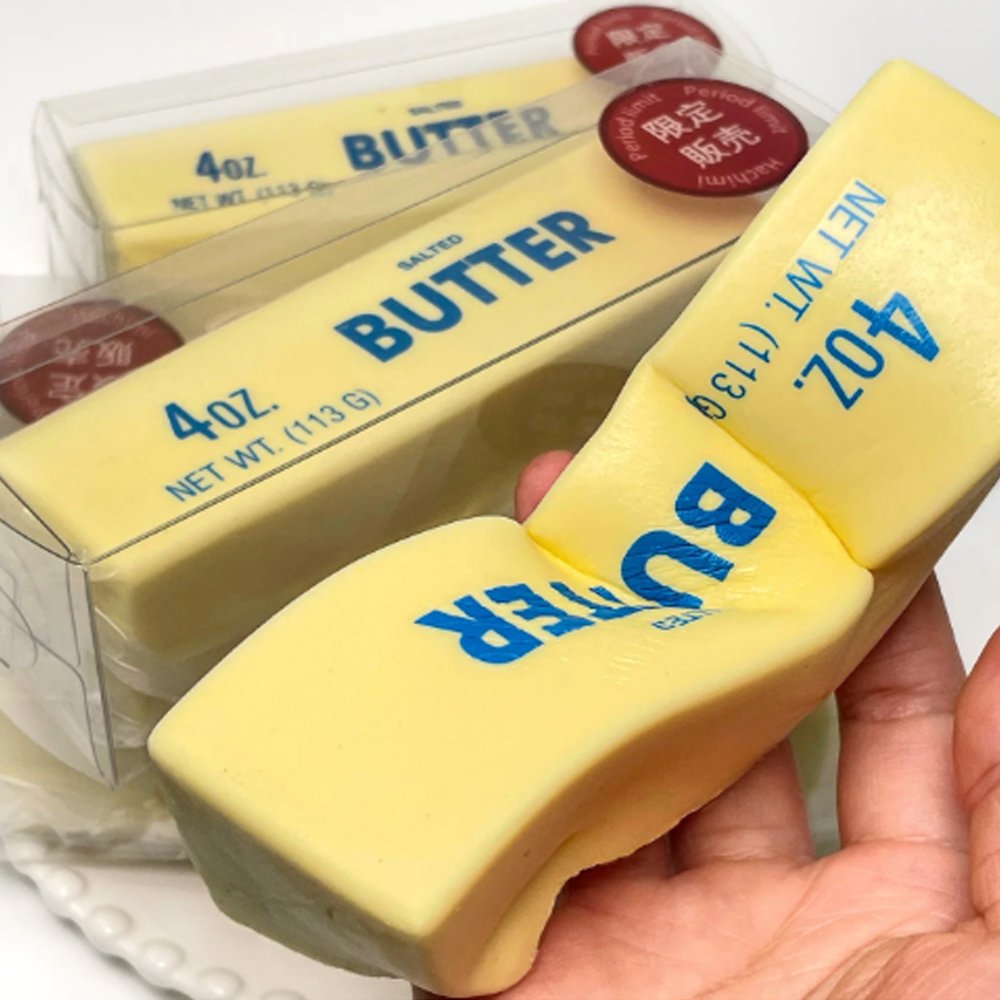 Realistic yellow butter stick squishy stress toy with blue lettering "4oz Salted Butter"