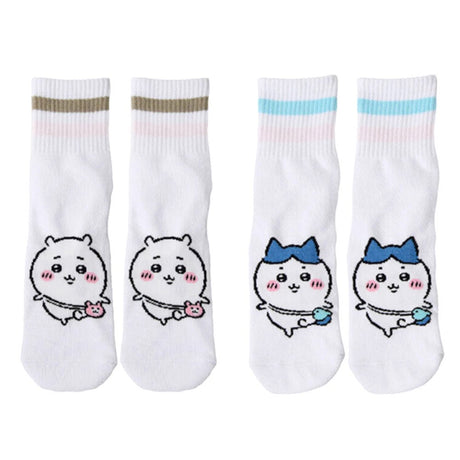 Featuring the pairs of officially licensed Chiikawa white crew-length socks, pink one holding a pink bear crossbody pouch and blue one holding a blue fish crossbody pouch.