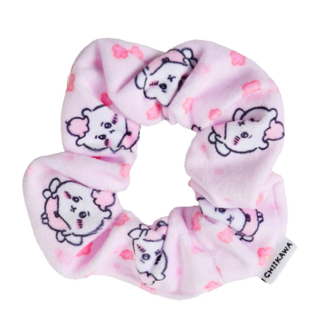 A pastel pink, plush fabric hair scrunchie featuring an all-over print of the officially licensed Chiikawa character with pink flower accents