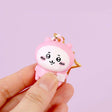 Pink Chiikawa character keychain held by a hand against a light purple background