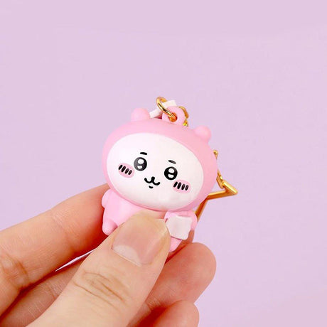 Pink Chiikawa character keychain held by a hand against a light purple background