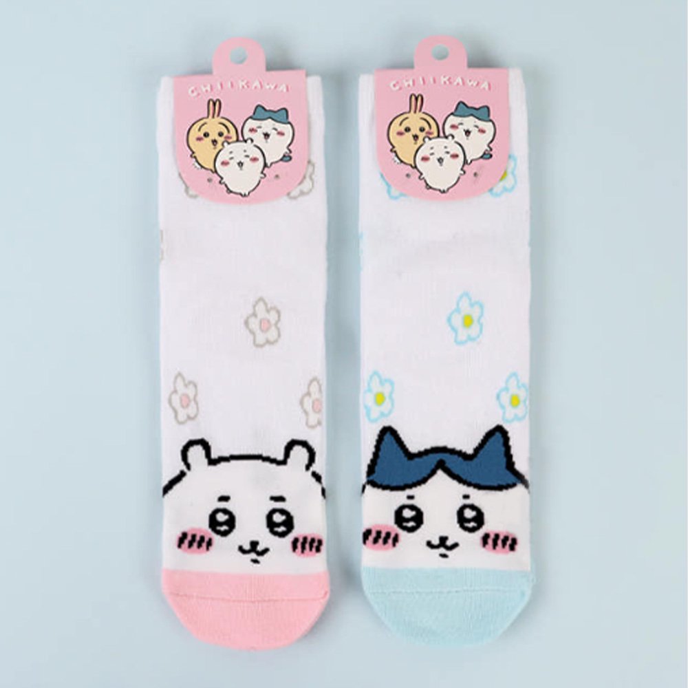 Featuring the pairs of officially licensed Chiikawa white crew-length socks, pink one surrounded by small pink-and-white flowers and blue one surrounded by blue-and-yellow flowers.