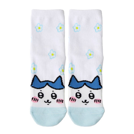 Featuring the pairs of officially licensed Chiikawa white crew-length socks, pink one surrounded by small pink-and-white flowers and blue one surrounded by blue-and-yellow flowers.