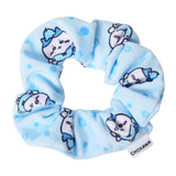 A pastel blue, soft plush hair scrunchie decorated with an all-over print of the Hachiware character from officially licensed Chiikawa