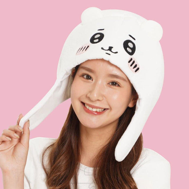 An officially licensed white Chiikawa plush character hat with embroidered eyes, blushing cheeks, and long ear flaps.