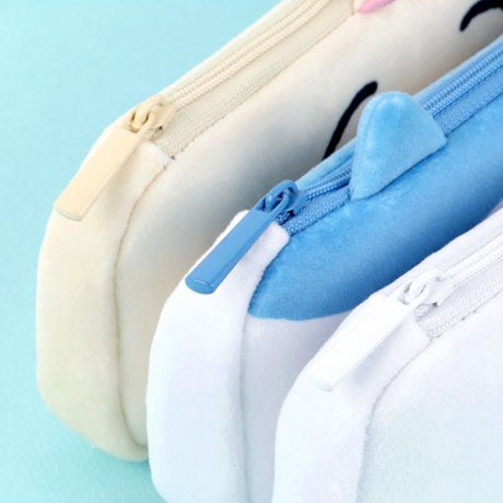 Three officially licensed plush Chiikawa character pencil cases featuring: the yellow-colored with Usagi's face and long ears; the white with Chiikawa's face; the white and blue with Hachiware's face and blue ears. Each pouch features embroidered eyes, pink cheeks, and a top zipper.