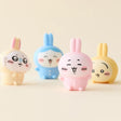 Officially licensed Chiikawa soft vinyl figures featuring Chiikawa, Hachiware, Momonga, and Usagi wearing colorful bunny-ear outfits
