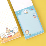 Officially licensed Chiikawa memo pads, one featuring a blue aquatic theme and the other a colorful comic book panel design. The interior pages show detailed character illustrations of Chiikawa, Hachiware, and Usagi.