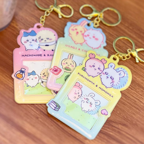 Colorful, officially licensed Chiikawa photo frame keychains featuring pastel gradients, character illustrations, and transparent window slots. Gold keyrings and lobster clasps are attached at the top of each charm holder.