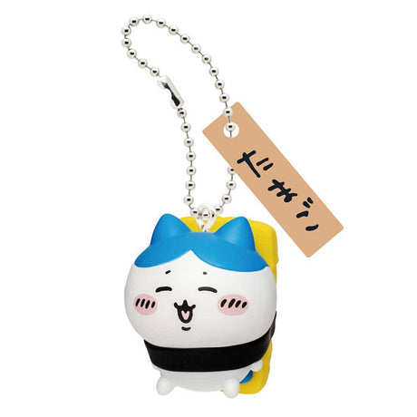 Front view of the officially licensed Hachiware egg sushi keychain from the Chiikawa blind box series. Blue-eared Hachiware lying under a yellow egg omelet (Tamago) tied with seaweed, complete with a ball chain and wooden tag