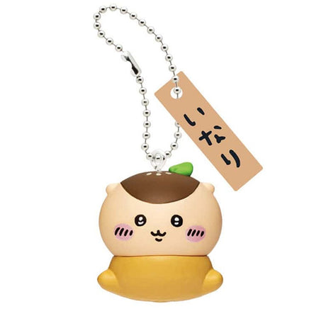Front view of the officially licensed Kurimanju Inari sushi keychain from the Chiikawa blind box series. Kurimanju nestled inside a golden-brown fried tofu pocket (Inari), complete with a silver ball chain and Japanese wooden tag