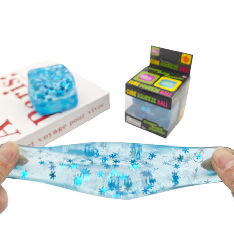 Translucent cube-shaped glitter squishy stress balls in purple, green, light blue, and pink filled with shimmering sparkles