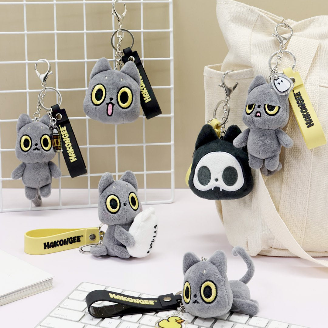 Plush keychains with black cat design on a white grid background, featuring the brand 'Hakongee'.