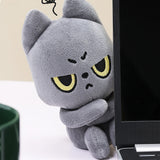 Black cat plush toy with cartoonish face next to a laptop
