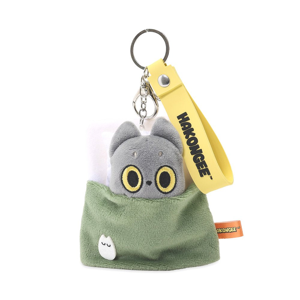 An officially licensed Hakongee cat plush keychain made by WSL, featuring the character tucked into a cozy green blanket with a pillow