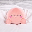 An officially licensed soft, round pink Kirby plush cushion resting peacefully with embroidered closed eyes and rosy cheeks