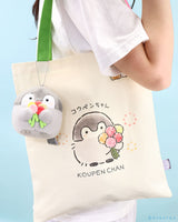 Koupen Chan Canvas Tote Bag: Person holding an official licensed cotton tote bag with the penguin holding a flower bouquet and an attached plush flower charm