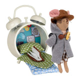 Levlovs' traveling mouse plush wearing a hooded coat and hat stands next to a cream-colored alarm clock structure outfitted as a tiny bedroom