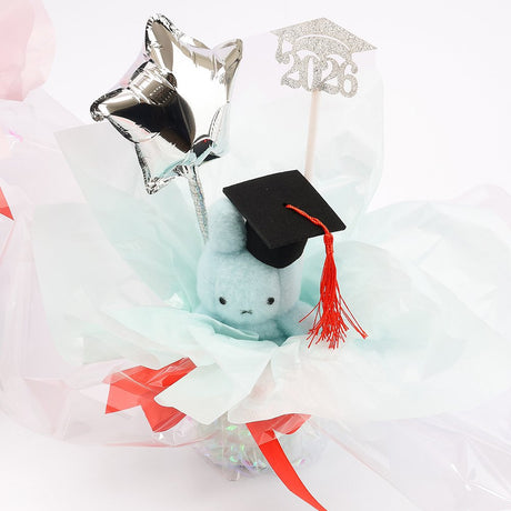 An officially licensed Class of 2026 Miffy graduation gift set featuring soft pink, orange, and blue color Miffy plush wearing black graduation caps. The characters are arranged like a bouquet with silver star balloons and "Congrats Grad" decorations.