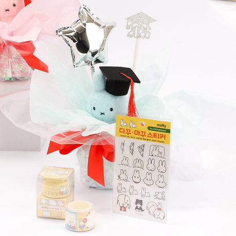 An officially licensed Class of 2026 Miffy graduation gift set featuring soft pink, orange, and blue color Miffy plush wearing black graduation caps. The characters are arranged like a bouquet with silver star balloons and "Congrats Grad" decorations.