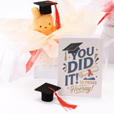 An officially licensed Class of 2026 Miffy graduation gift set featuring soft pink, orange, and blue color Miffy plush wearing black graduation caps. The characters are arranged like a bouquet with silver star balloons and "Congrats Grad" decorations.
