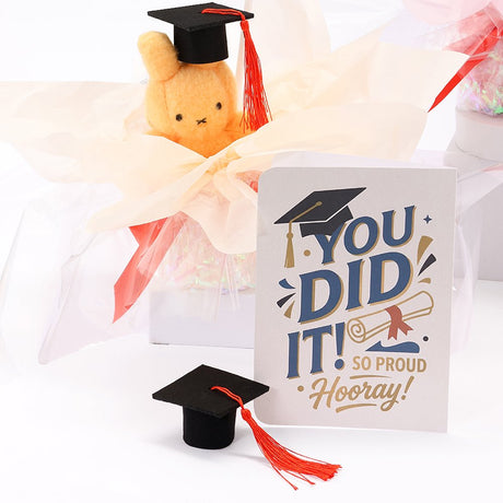 An officially licensed Class of 2026 Miffy graduation gift set featuring soft pink, orange, and blue color Miffy plush wearing black graduation caps. The characters are arranged like a bouquet with silver star balloons and "Congrats Grad" decorations.