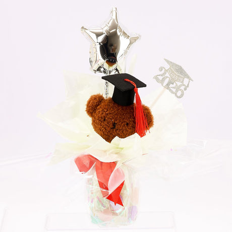 An officially licensed Class of 2026 Miffy graduation gift set featuring yellow, orange, green, and blue color Miffy plush and Boris plush wearing black graduation caps. The characters are arranged like a bouquet with silver star balloons and "Congrats Grad" decorations.