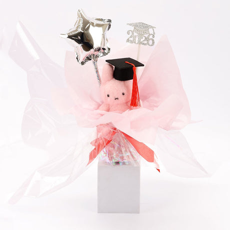 An officially licensed Class of 2026 Miffy graduation gift set featuring soft pink, orange, and blue color Miffy plush wearing black graduation caps. The characters are arranged like a bouquet with silver star balloons and "Congrats Grad" decorations.