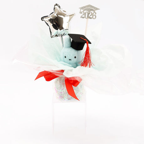An officially licensed Class of 2026 Miffy graduation gift set featuring soft pink, orange, and blue color Miffy plush wearing black graduation caps. The characters are arranged like a bouquet with silver star balloons and "Congrats Grad" decorations.