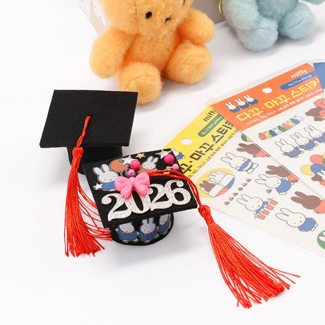 An officially licensed Class of 2026 Miffy graduation gift set featuring soft pink, orange, and blue color Miffy plush wearing black graduation caps. The characters are arranged like a bouquet with silver star balloons and "Congrats Grad" decorations.
