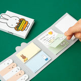 Officially licensed Miffy sticky note booklets featuring different covers—one showing Miffy holding a tray of orange flowers on a white background, and the other showing Miffy eating with a blue spoon on a yellow background