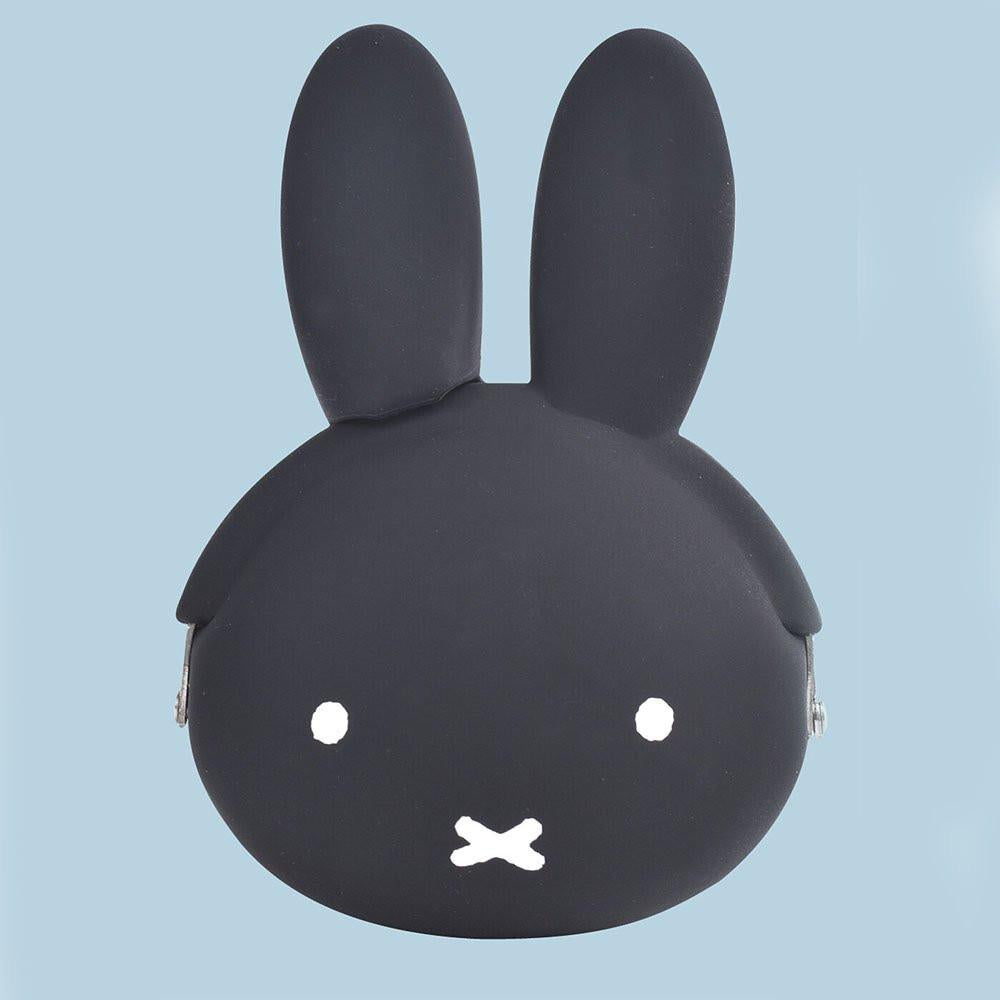  A close-up photograph of a woman's hand holding a small, Jet Black Miffy character pouch made of soft, flexible premium silicone. Part of the Official Miffy Mini Pochibi series, which includes a matt White aesthetic alternative; a durable, tactile, and minimalist Zen bunny purse designed for adult mental wellness and nostalgic daily organization. 