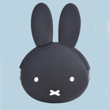  A close-up photograph of a woman's hand holding a small, Jet Black Miffy character pouch made of soft, flexible premium silicone. Part of the Official Miffy Mini Pochibi series, which includes a matt White aesthetic alternative; a durable, tactile, and minimalist Zen bunny purse designed for adult mental wellness and nostalgic daily organization. 