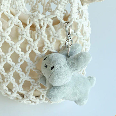A Muted grey Miffy bunny  plush keychain with a minimalist X-shaped mouth. This classic cream-white collector's item offers visual rest and childhood nostalgia for millennials decorating bag or your minimalist workspaces.