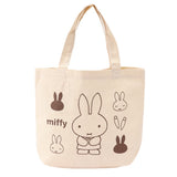 An officially licensed Miffy canvas tote bag in a cream color, showing various Miffy poses and carrots in brown ink.