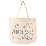 An officially licensed Miffy canvas tote bag in a cream color, surrounded by flowers with the name "Miffy" in a grey script font.