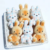 Officially licensed Miffy plush keychains seated in a white basket. The set includes two styles: bread or toast with its orange-brown color, and one in a light blue, white, and red plaid/checkered fabric. Both Miffy dolls feature embroidered eyes and the signature 'X' mouth.