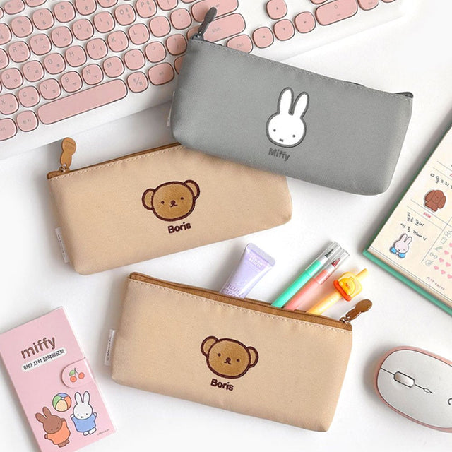 Two slim canvas pencil cases: one grey featuring an embroidered Miffy face and one tan featuring Boris Bear. Both cases have character-shaped zipper pulls.