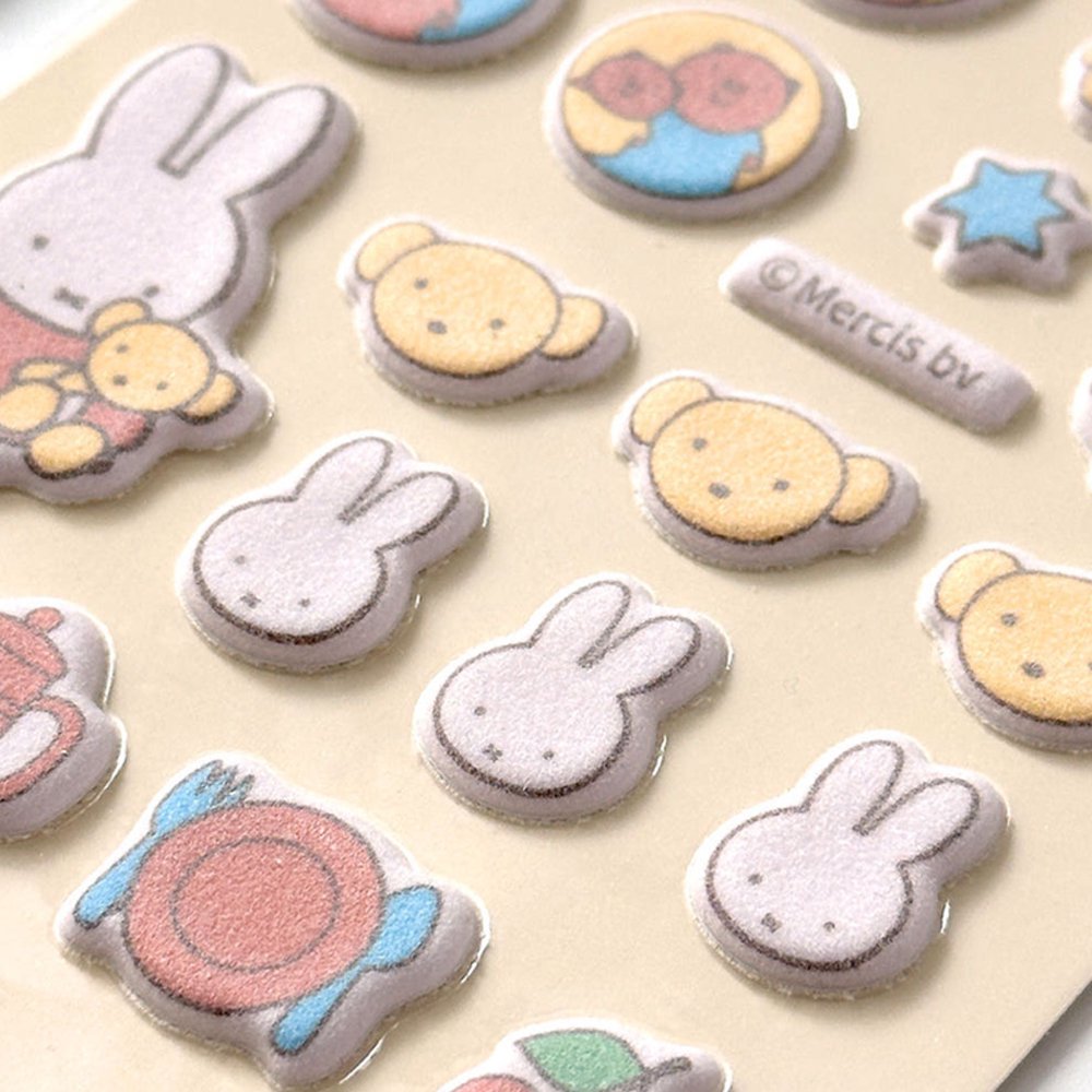 Two officially licensed Miffy Fuzzy Cushion Sticker sheets in cream and mint colors, showcased alongside a decorated phone case and earbud case. The sticker sheets are filled with small, textured, raised stickers depicting Miffy the bunny and her friends engaging in daily activities like baking and gardening.

