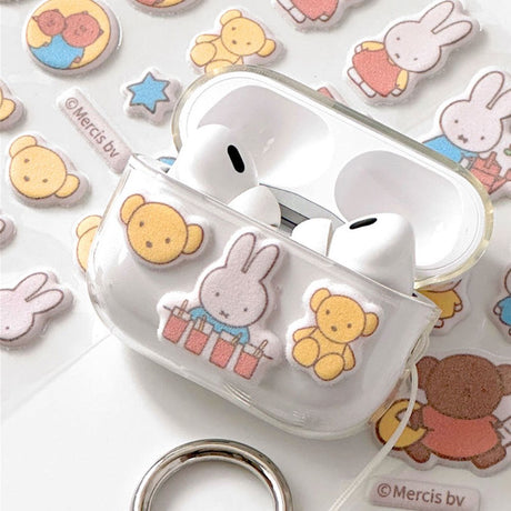 Two officially licensed Miffy Fuzzy Cushion Sticker sheets in cream and mint colors, showcased alongside a decorated phone case and earbud case. The sticker sheets are filled with small, textured, raised stickers depicting Miffy the bunny and her friends engaging in daily activities like baking and gardening.
